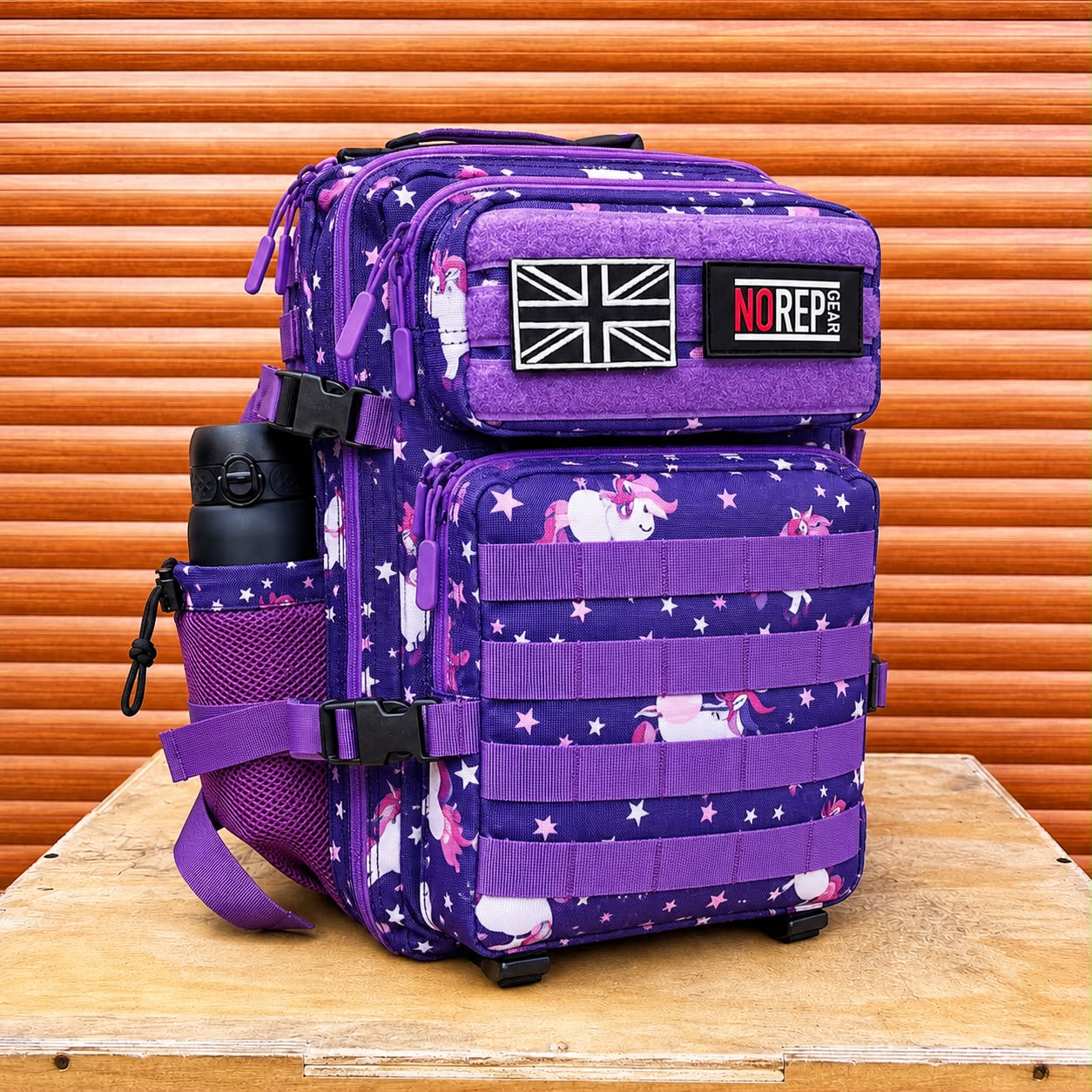 A purple tactical backpack with a unicorn and star pattern, featuring a black NRG brand patch